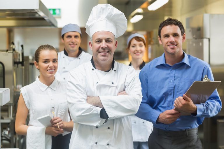 Gruppe von Köchen und Restaurantmitarbeitern in einer professionellen Küche.